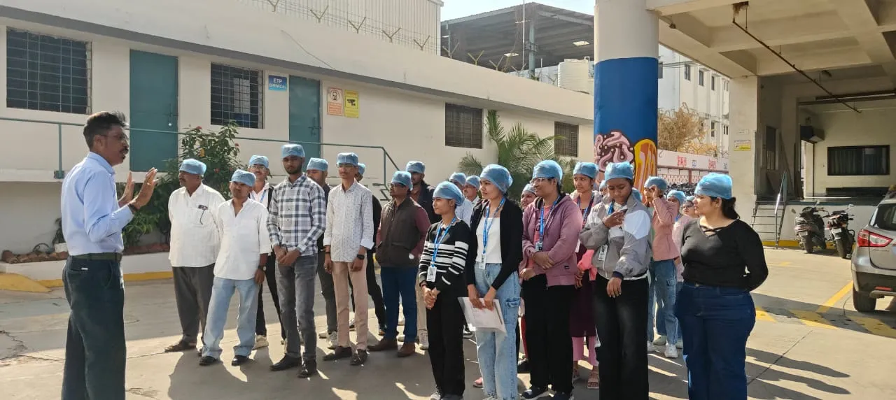 A plant supervisor explaining the manufacturing process and safety standards to visiting students